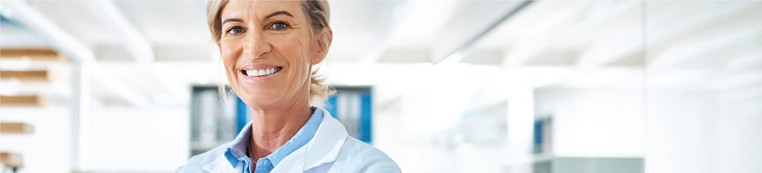 Smiling female lab technician wearing protective gloves and lab coat, demonstrating essential lab safety practices – Qor Labs