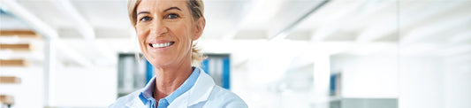 Smiling female lab technician wearing protective gloves and lab coat, demonstrating essential lab safety practices – Qor Labs